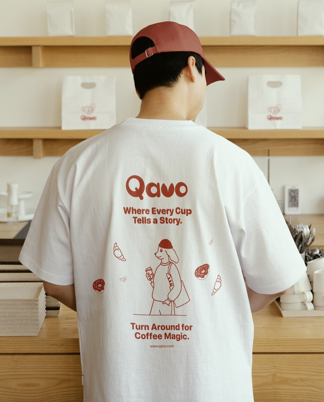 Qavo employee wearing branded T-shirt with mascot illustration and brand slogan